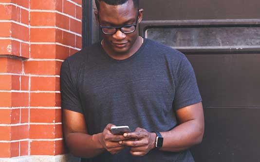 A man with glasses watching his mobile device