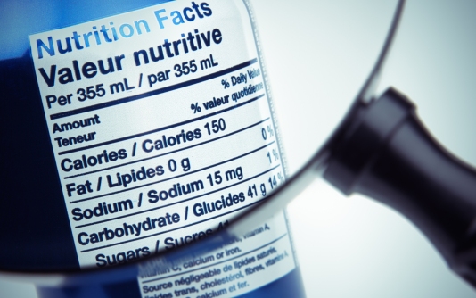 The nutrition label on a soda can is examined under a magnifying glass
