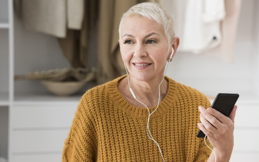 A woman wearing earphones is holding a phone