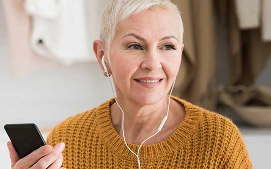A woman wearing earphones is holding a phone