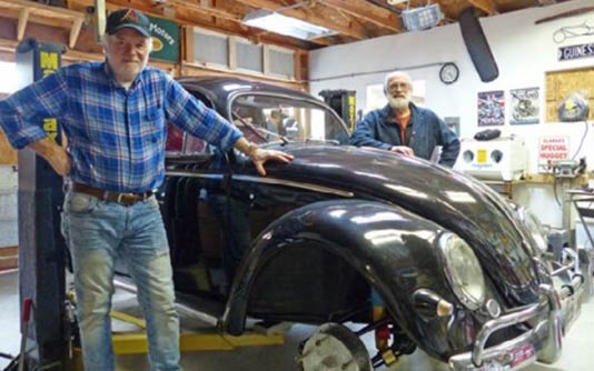 John Chris Beresford standing next to his black beetle car