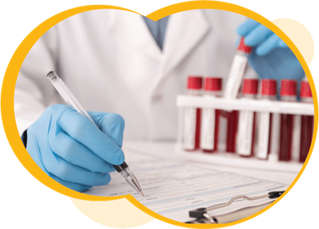 A medical professional writing on a clipboard while analyzing blood samples. They are wearing a white lab coat and blue examination gloves.