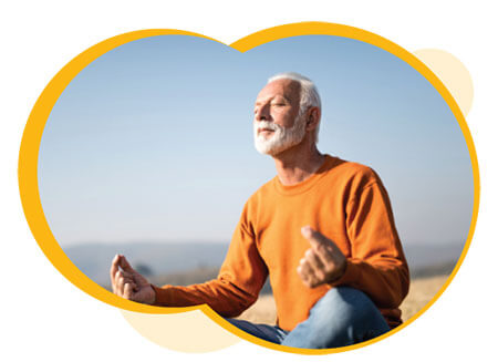 An older male with greay hair and beard, seating, meditating