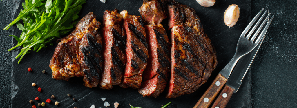 A steak sliced up with garnish on top and on the side