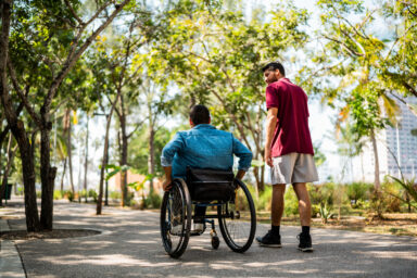 Two people with light skin talking and spending time outdoors together. One of them is walking and the other is using a wheelchair. Deux personnes &agrave; la peau claire qui discutent et passent du temps ensemble &agrave; l&rsquo;ext&eacute;rieur. L&rsquo;une marche et l&rsquo;autre est en fauteuil roulant. 